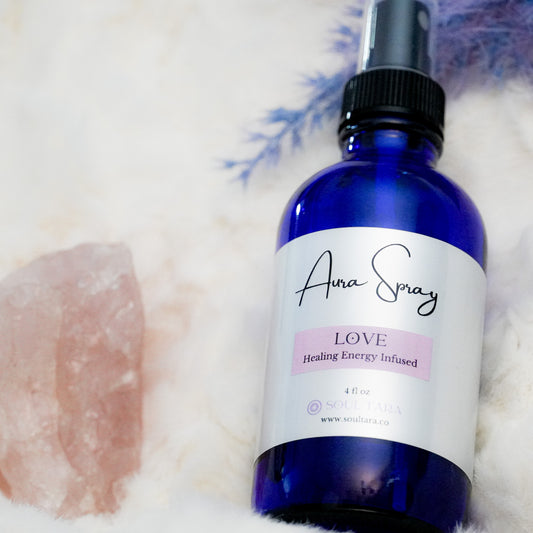 Aura spray bottle with a rose quarts crystal on a white fluffy cloth